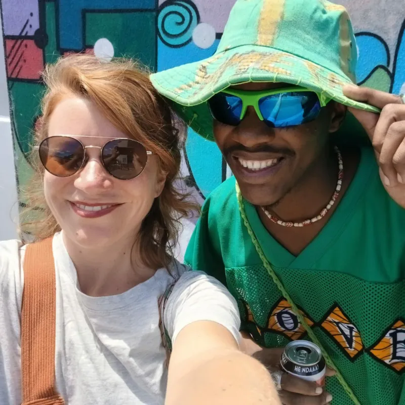 Guest and Masande taking a selfie in front of a mural